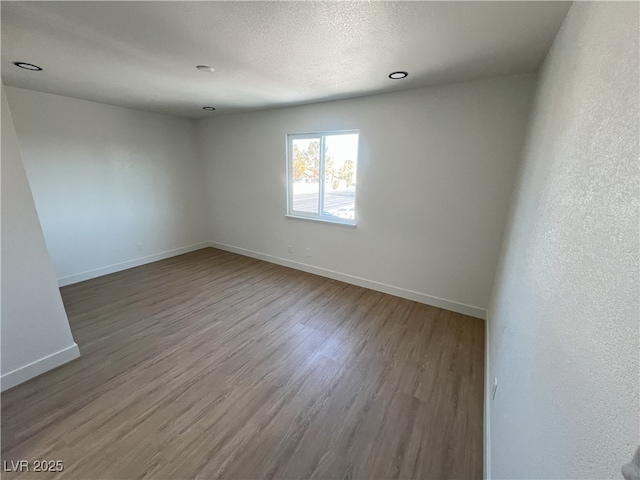 unfurnished room featuring wood-type flooring and a textured ceiling