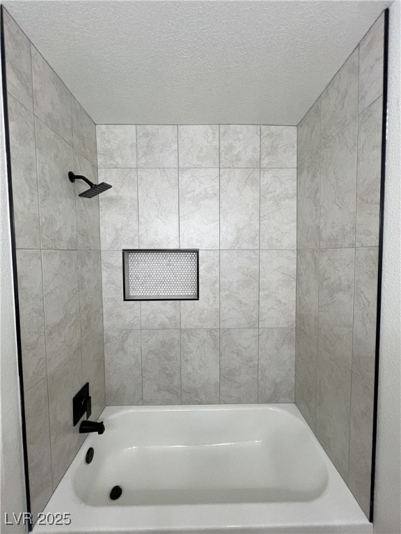 bathroom featuring tiled shower / bath and a textured ceiling