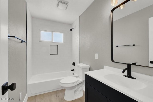 full bathroom featuring vanity, tiled shower / bath, wood-type flooring, and toilet