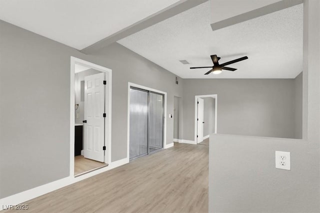 spare room with ceiling fan, lofted ceiling, light hardwood / wood-style flooring, and a textured ceiling