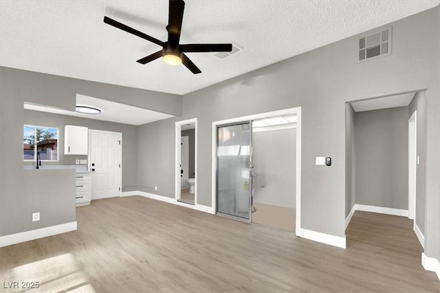 unfurnished living room with ceiling fan, light hardwood / wood-style flooring, and a textured ceiling