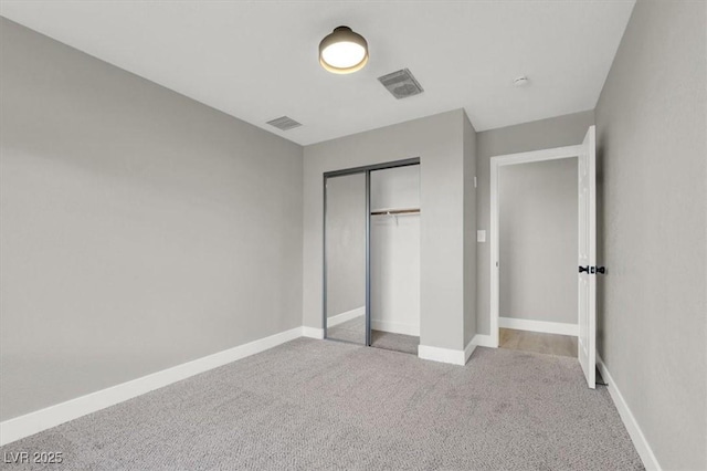 unfurnished bedroom with light colored carpet and a closet