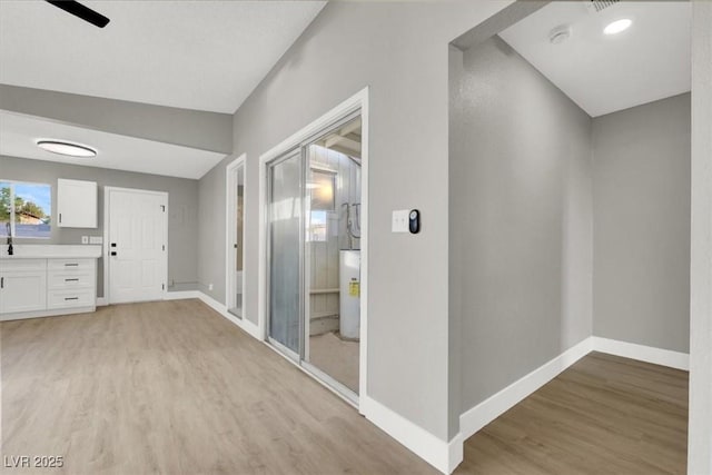 corridor featuring water heater and light hardwood / wood-style floors