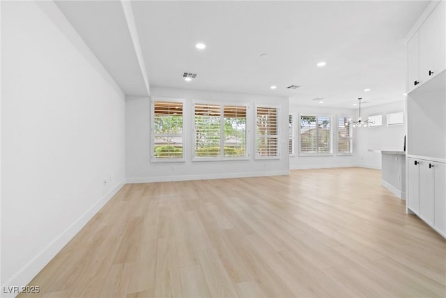 unfurnished living room featuring a notable chandelier and light hardwood / wood-style flooring