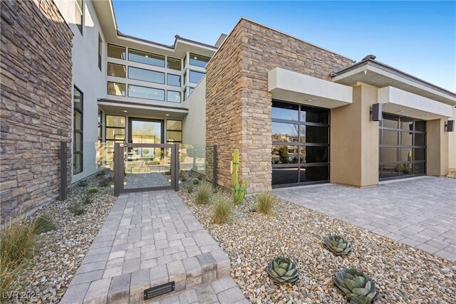 property entrance with stone siding, a gate, and stucco siding