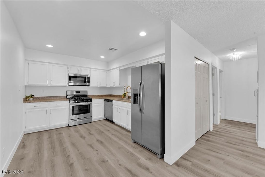 kitchen with appliances with stainless steel finishes, sink, light wood-type flooring, and white cabinets