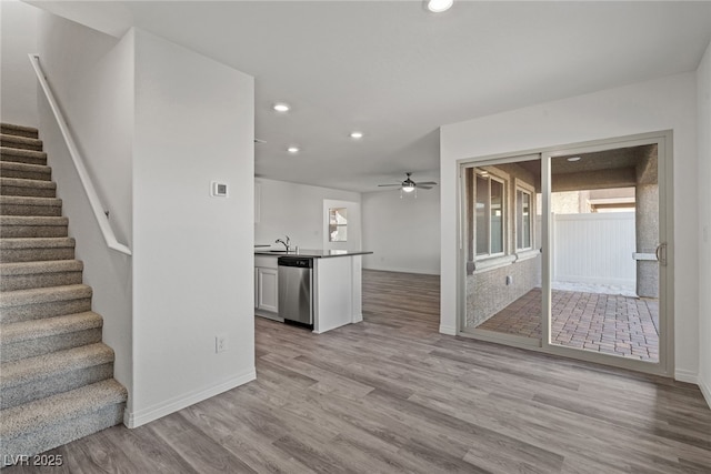 unfurnished living room featuring ceiling fan, sink, and light hardwood / wood-style flooring