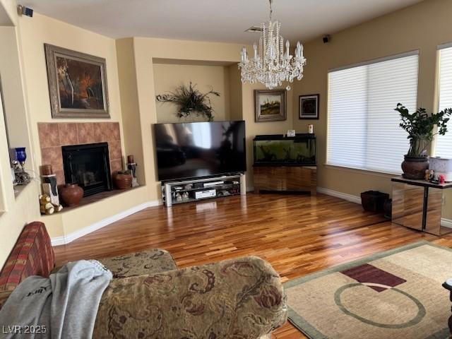 living room featuring an inviting chandelier, hardwood / wood-style floors, and a tile fireplace