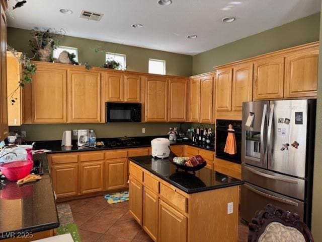 kitchen with dark tile patterned floors, a kitchen island, and black appliances