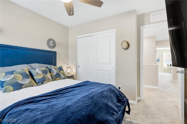 bedroom with light colored carpet, ceiling fan, and a closet