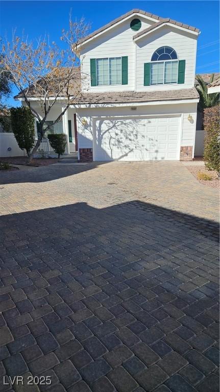 traditional home with decorative driveway and an attached garage