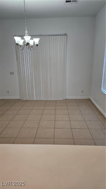 unfurnished room featuring a chandelier, visible vents, baseboards, and light tile patterned flooring