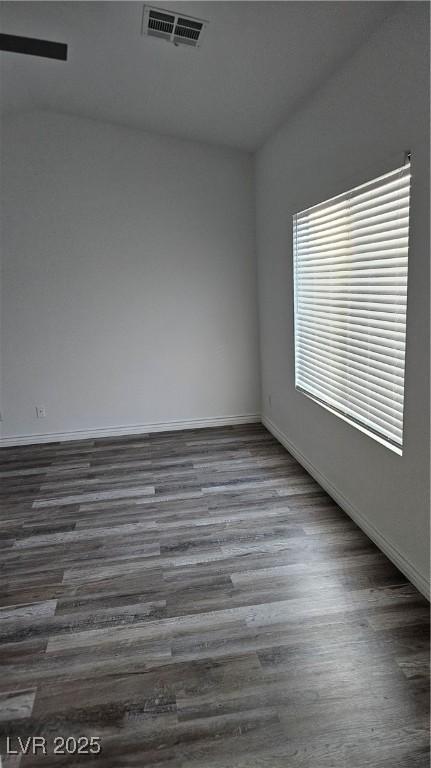 spare room with dark wood-style floors, visible vents, and baseboards