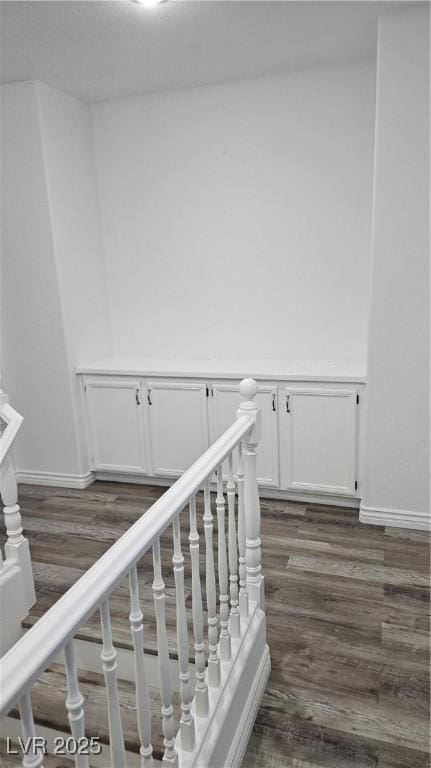 staircase featuring wood finished floors and baseboards