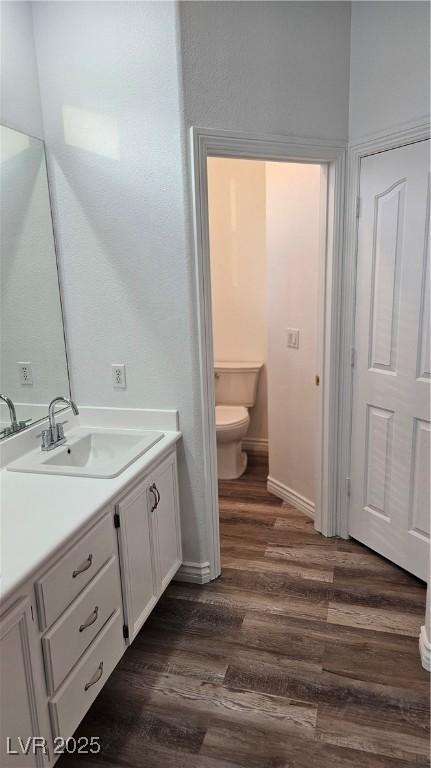 bathroom with toilet, wood finished floors, and vanity