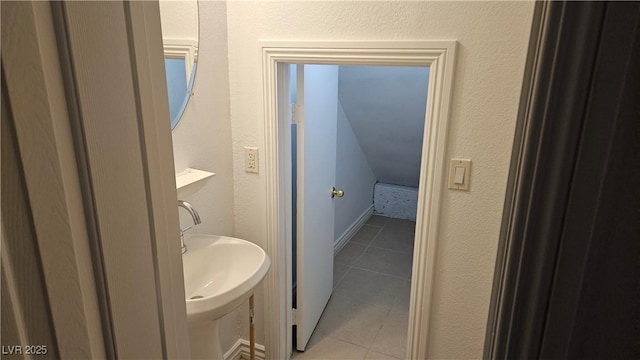 bathroom featuring tile patterned floors, a sink, and a textured wall