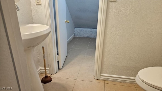 bathroom with tile patterned floors, toilet, baseboards, and a textured wall