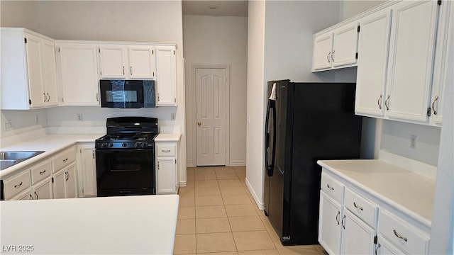 kitchen with light tile patterned floors, black appliances, light countertops, and white cabinetry