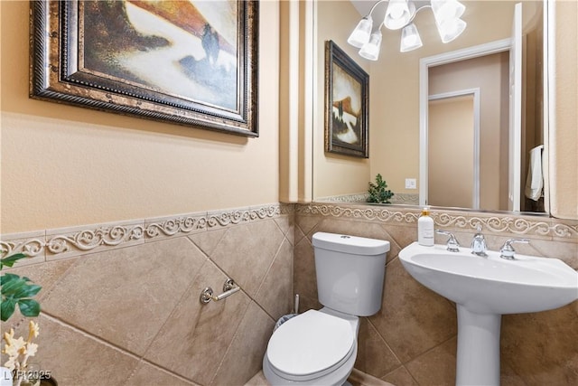 bathroom featuring wainscoting, toilet, and tile walls