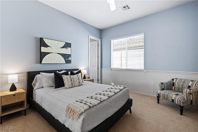 carpeted bedroom with visible vents and wainscoting