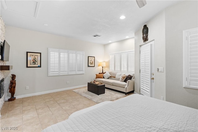 bedroom with a stone fireplace and light tile patterned floors