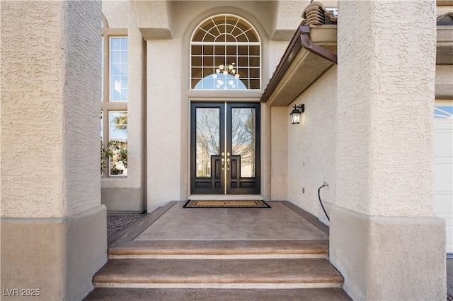 property entrance with stucco siding and french doors