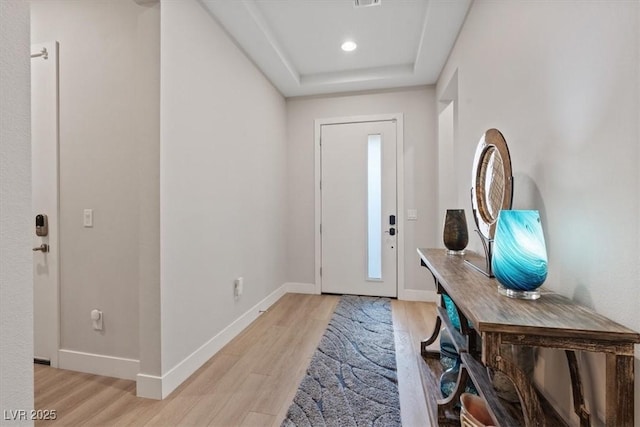 entryway with a tray ceiling and light hardwood / wood-style floors