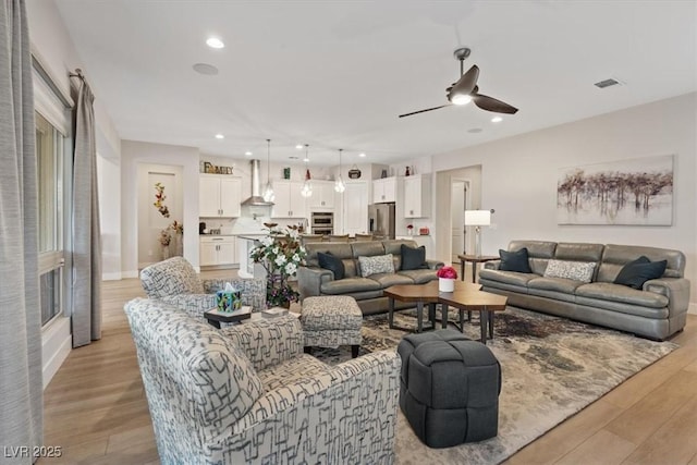 living room with ceiling fan and light wood-type flooring