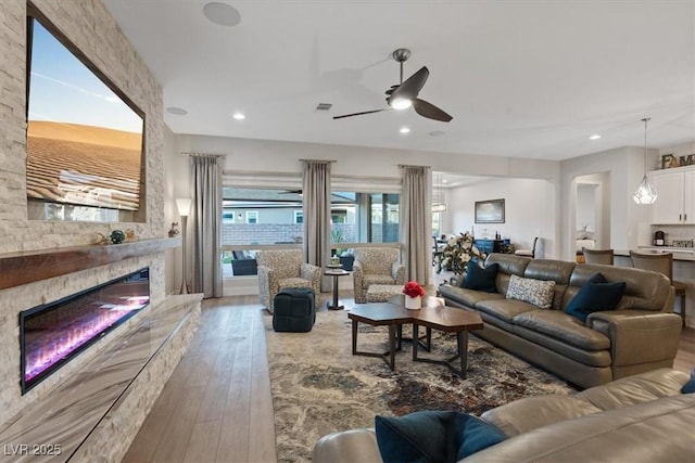 living room with hardwood / wood-style flooring, a large fireplace, and ceiling fan