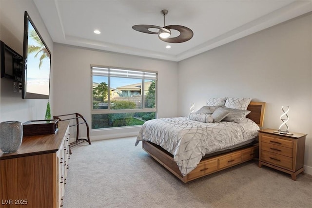 carpeted bedroom with a raised ceiling and ceiling fan