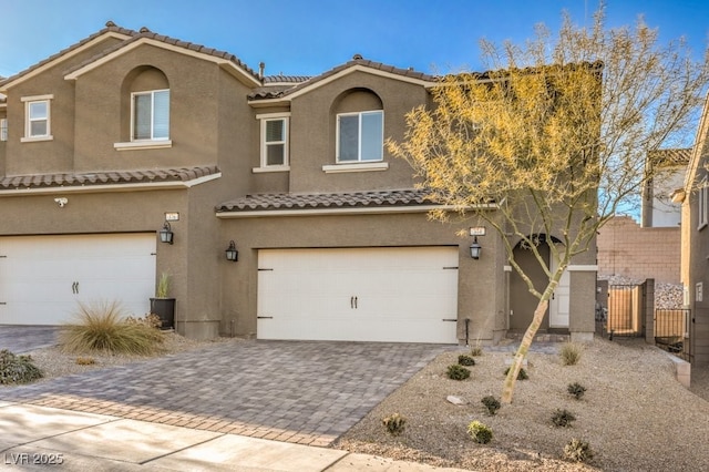 view of front of home with decorative driveway, an attached garage, and stucco siding