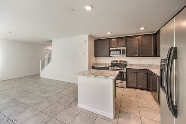 kitchen featuring dark brown cabinetry, light stone counters, a center island, light tile patterned floors, and stainless steel appliances