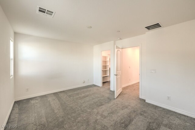 unfurnished bedroom with a spacious closet and carpet flooring