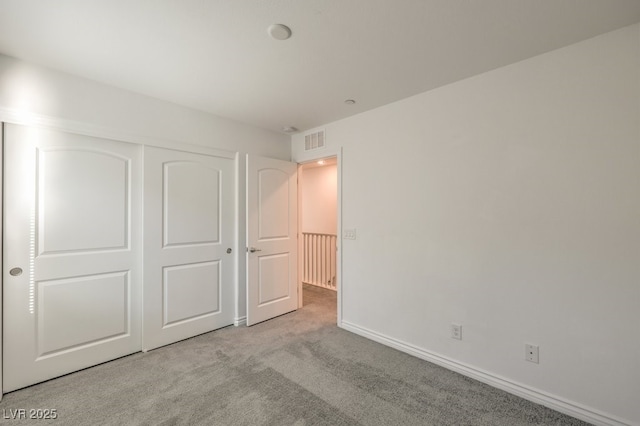 unfurnished bedroom featuring light carpet and a closet