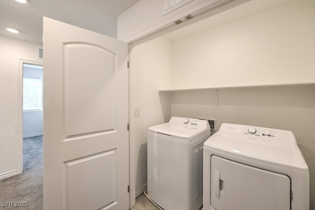 clothes washing area featuring light carpet and washing machine and clothes dryer