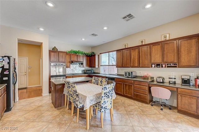 kitchen featuring light tile patterned floors, appliances with stainless steel finishes, a kitchen breakfast bar, extractor fan, and a kitchen island