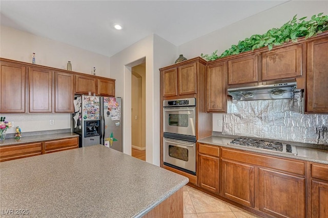 kitchen featuring light tile patterned flooring, appliances with stainless steel finishes, exhaust hood, and decorative backsplash