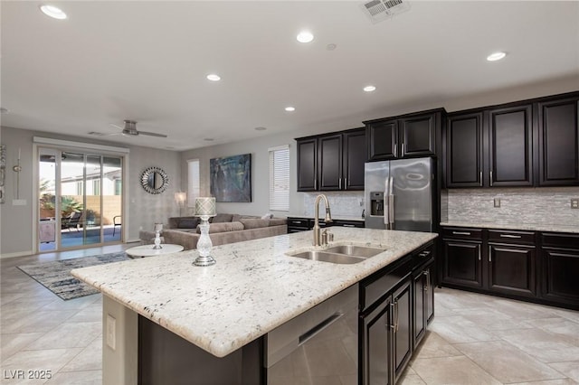 kitchen with stainless steel appliances, a sink, visible vents, open floor plan, and tasteful backsplash