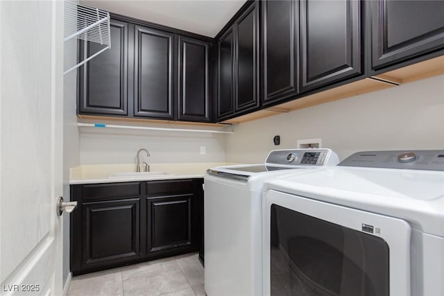 washroom featuring cabinet space, a sink, washing machine and clothes dryer, and light tile patterned floors