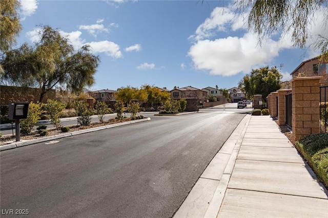 view of street featuring sidewalks, a residential view, a gated entry, and curbs