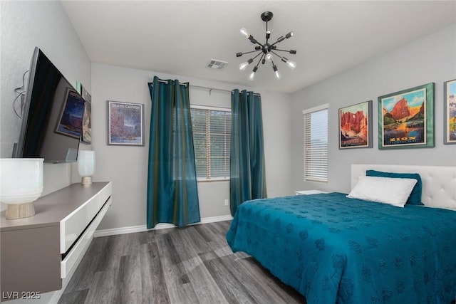 bedroom featuring a notable chandelier, visible vents, baseboards, and wood finished floors