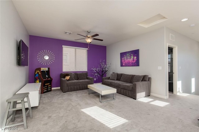 carpeted living room with attic access, visible vents, baseboards, and a ceiling fan