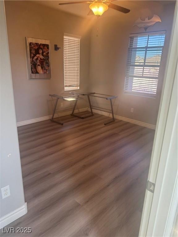 empty room with a ceiling fan, baseboards, and wood finished floors