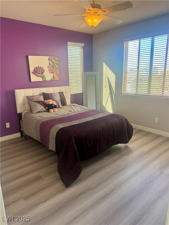 bedroom featuring a ceiling fan, baseboards, and wood finished floors