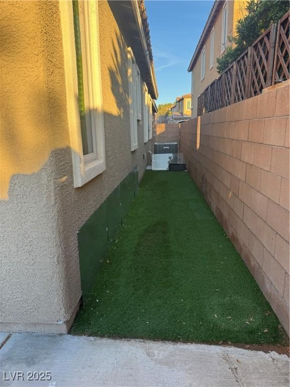 view of property exterior with a fenced backyard, a lawn, and stucco siding