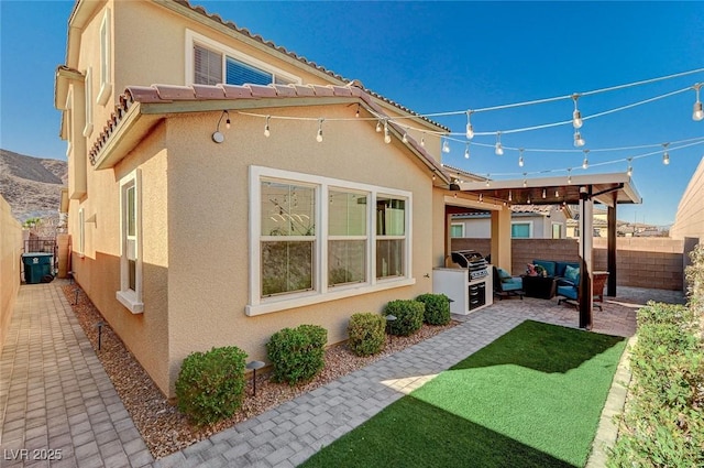 back of property with an outdoor kitchen, an outdoor living space, and a patio