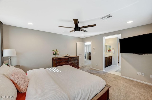 bedroom with light colored carpet, ceiling fan, and ensuite bath