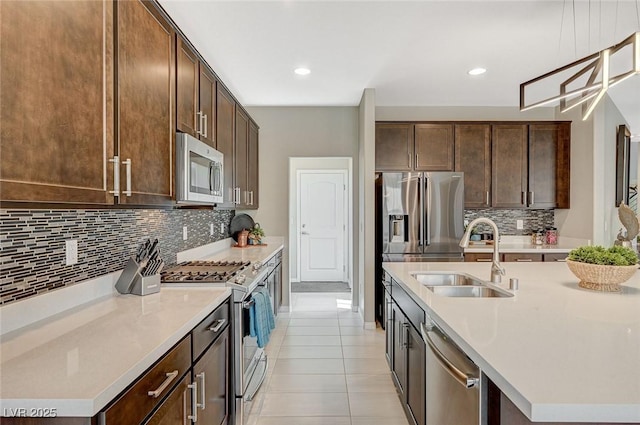 kitchen featuring sink, tasteful backsplash, dark brown cabinets, a center island with sink, and appliances with stainless steel finishes