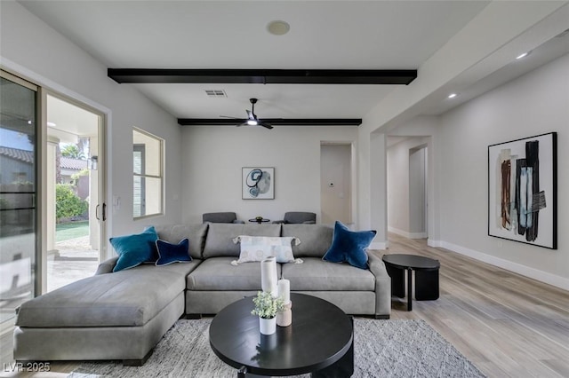 living room with ceiling fan, light hardwood / wood-style floors, and beamed ceiling