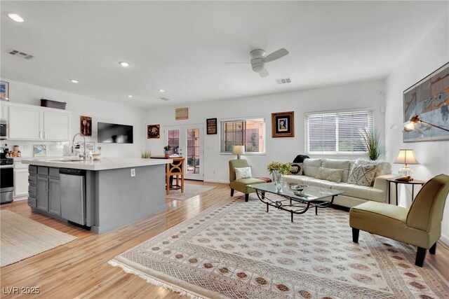 living room with ceiling fan, sink, and light hardwood / wood-style floors